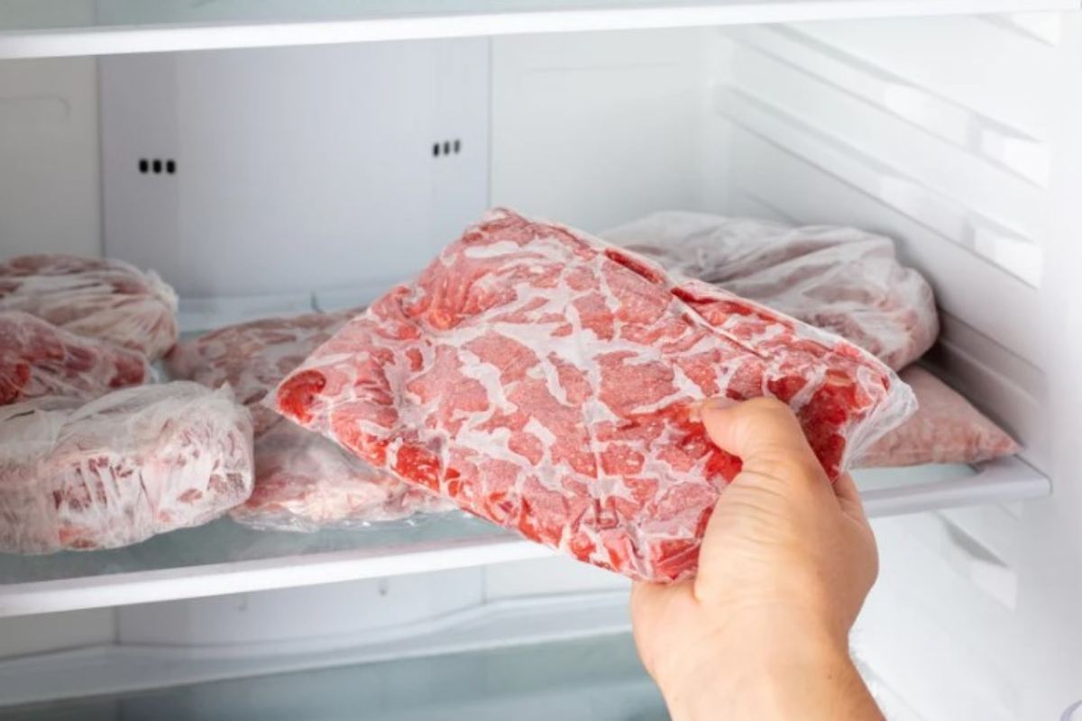 Persona tira fuori la carne congelata dal congelatore