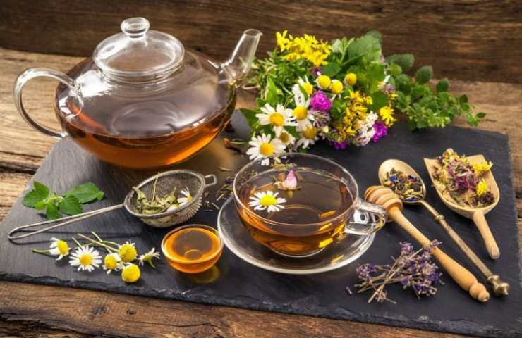 Teiera con tisana su un vassoio con diversi ingredienti 